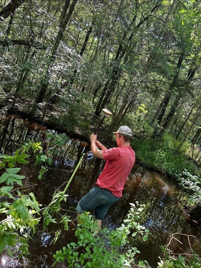 HSA survey crew taking a GPS shot along a creek bank